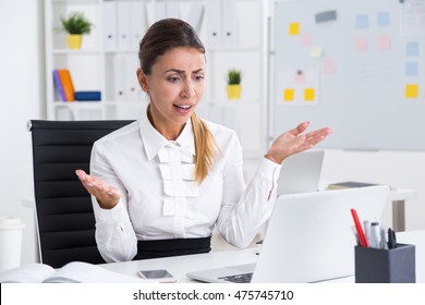 Disappointed Business Lady Sitting At Her Workplace Looking At Laptop Screen And Waving Hands. Concept Of Technical Difficulties