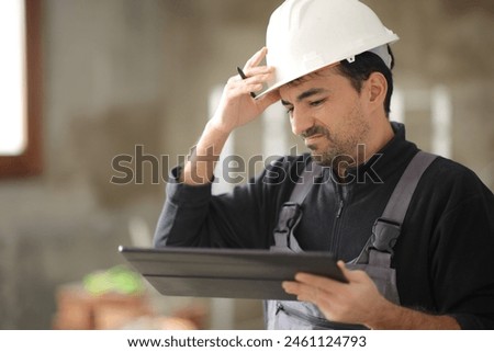 Disappointed construction worker checking tablet in a house