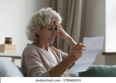 Disappointed Elderly Woman Sitting On Couch In Living Room Feels Frustrated By Bad News, Reading Paper Postal Correspondence, Bank Notice About Debt, Notification Of Eviction, Negative Letter Concept