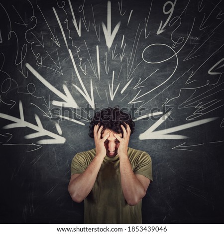 Disappointed guy covers face with his hands, looking down introverted and depressed, being under pressure as multiple arrows points tension negativity to his head. Person suffering emotional breakdown