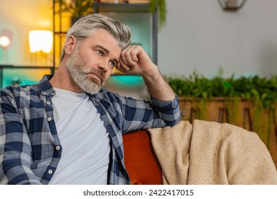 Disappointed man sits at home reflecting on moral distress after quarrel break-up or divorce problem feeling bad annoyed ill sick. Sad middle-aged guy in room contemplates the emotional aftermath - Powered by Shutterstock