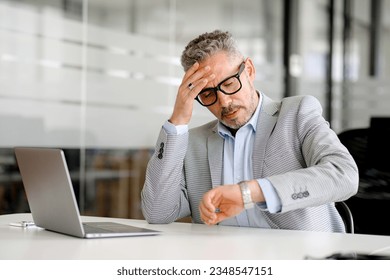 Disappointed mature businessman in formal wear looking at the watch on his wrist and worrying about the deadline, has lack of time, male office employee forgot about meeting or appointment - Powered by Shutterstock