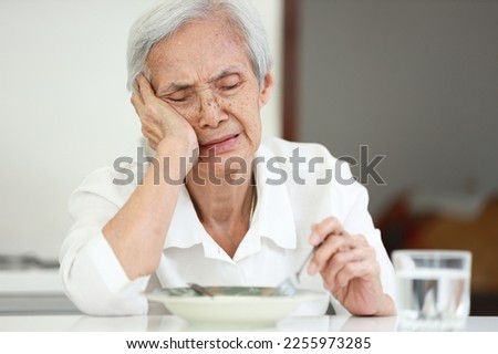 Disappointed old elderly people eating overnight food,she's sick of food,tired of eating same food,lacking flavor,Asian senior woman suffering from anorexia,loss of appetite,diet and nutrition concept