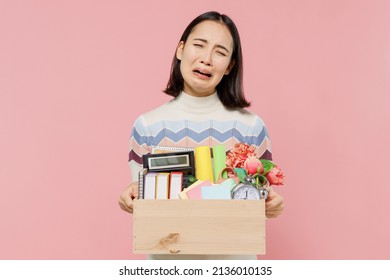 Disappointed Sad Teen Student Girl Of Asian Ethnicity In Sweater Backpack Hold Books Hold Box Of Stationery Cry Isolated On Pastel Plain Light Pink Background Education In University College Concept.