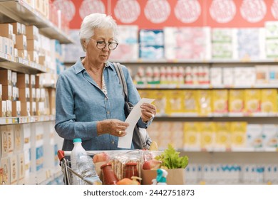 Disappointed senior customer checking the grocery receipt at the supermarket, expensive grocery concept - Powered by Shutterstock