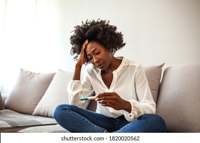 Disappointed woman getting unexpected result from pregnancy test kit. Sad young woman sitting alone on her bed. Sad Young Woman With Pregnancy Test At Home