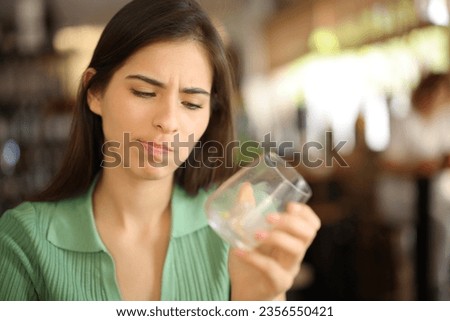 Disappointed woman looking at empty glass in a bar interior