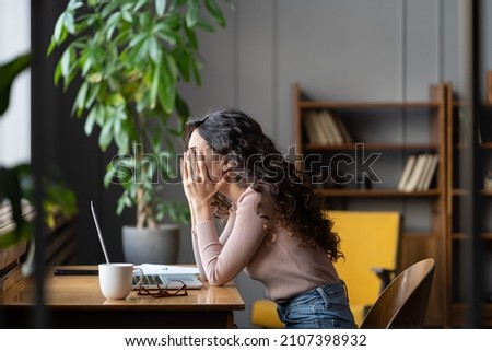 Disappointed woman office worker struggling through task, being unproductive, tired overworked female employee covering face with hands and thinking about solution while sitting at table with laptop