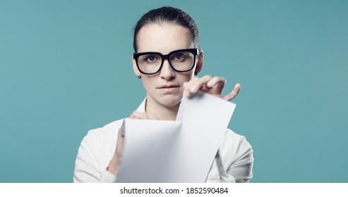 Disappointed woman ripping up a contract, she is tearing the document and staring at camera