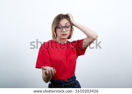 Disappointed young caucasian woman in fashion red shirt having nice glasses, keeping hand on head, thinking isolated on white background in studio. People sincere emotions, lifestyle concept.