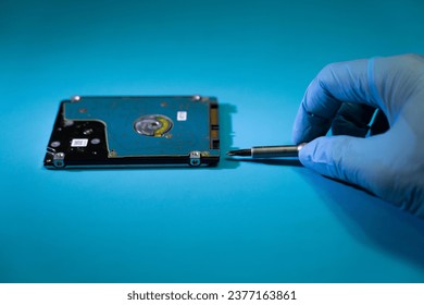 Disassemble the damaged hard disk using a screwdriver. blue background