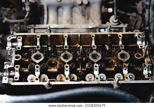 Disassembled car engine in oil. Cylinder head\
of an automobile engine. Inside the car being repaired. Sixteen\
valves. Car\
maintenance