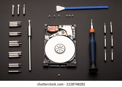 Disassembled computer hard drive, screwdrivers, bits, bolts and a microfiber swab