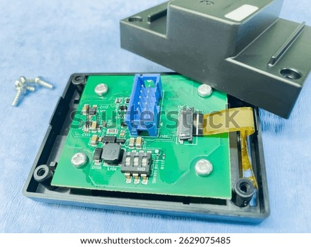 Disassembled electronic device exposing its internal components, including printed circuit board with connectors, screws, and ribbon cable
