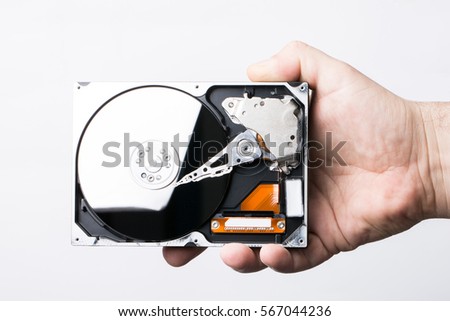 Disassembled hard disk drive in male hand on white background

