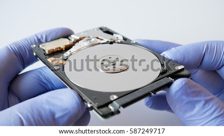 Disassembled hard disk drive in male hand on white background