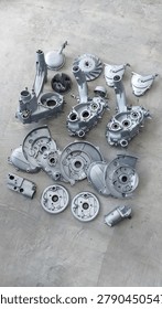 Disassembled internal combustion engine components meticulously laid out on a concrete workshop floor, prepared for cleaning, inspection, or reassembly for vehicle restoration.