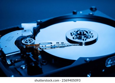 Disassembled open hard disk drive HDD of computer or laptop. Place it on a dark blue light background. the concept of data, hardware, and information technology