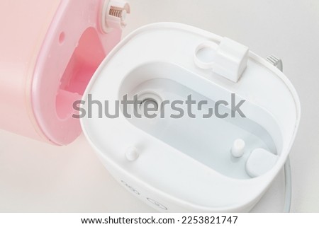 disassembled pink humidifier on a white background. the device saturates the air with the smallest particles of water, evaporating it.