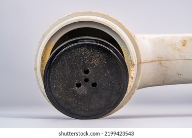 Disassembled White Dirty Handset Of Old Telephone. Black Round Part Of Speaker Or Microphone With Holes From Vintage Landline Phone On Gray Background. Broken Vintage Plastic Analog Telephone. Macro.