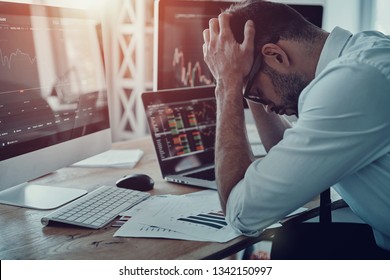 Disaster! Frustrated young businessman in formalwear keeping head in hands while sitting in the office - Powered by Shutterstock
