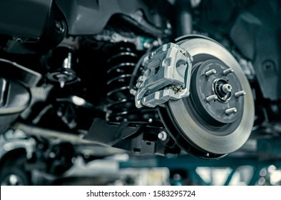 Disc brake of the vehicle for repair, in process of new tire replacement. Car brake repairing in garage.Suspension of car for maintenance brakes and shock absorber systems.Close up.