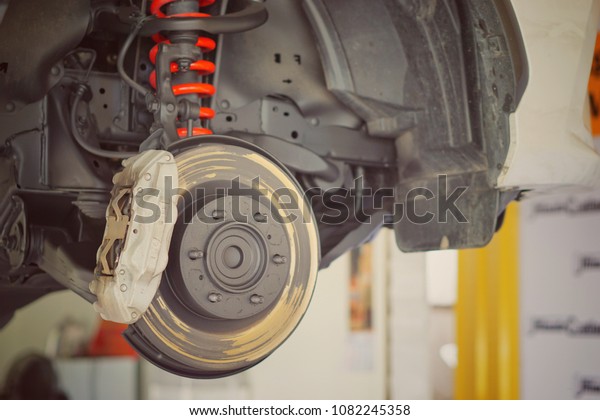 Disc brake of the vehicle for repair, in process of\
new tire replacement. Car brake repairing in service car.Close\
up.
