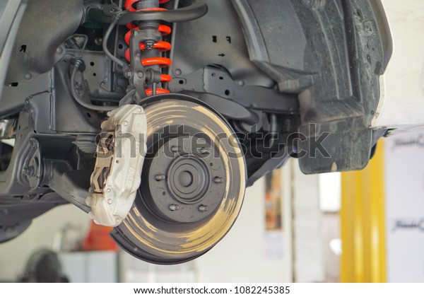 Disc brake of the vehicle for repair, in process of\
new tire replacement. Car brake repairing in service car.Close\
up.