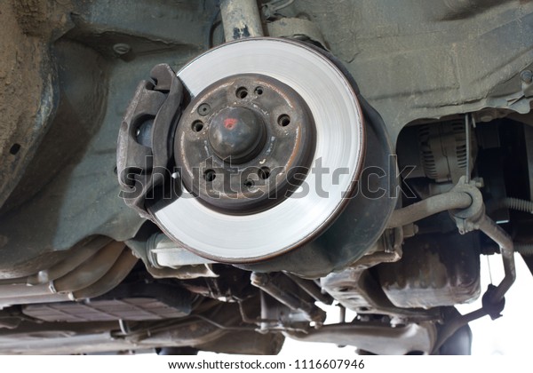 Disc\
brake of the vehicle for repair, in process of new tire\
replacement. Car brake repairing in garage.Close\
up