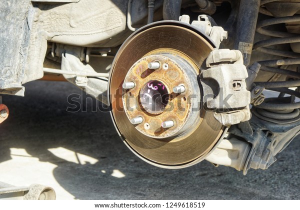 Disc brake of the vehicle for repair, \
in process of\
new tire replacement. \
Car brake repairing in garage.Close\
up.