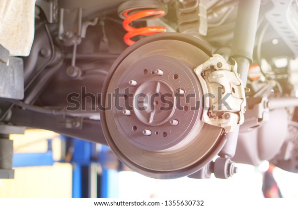 Disc brake of the vehicle for repair, in process of\
new tire replacement. Car brake repairing in garage.Car suspension\
with disc brake.I take care my car everytime for safety all of\
them. Close up.