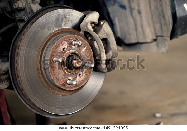 Disc\
brake of the vehicle for repair, in process of new tire\
replacement. Car brake repairing in garage.Close\
up.