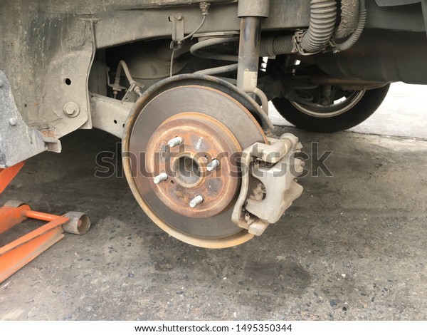 Disc brake of the vehicle for repair, in process of\
new tire replacement. Car brake repairing in garage.Car suspension\
with disc brake.I take care my car everytime for safety all of\
them. Close up.