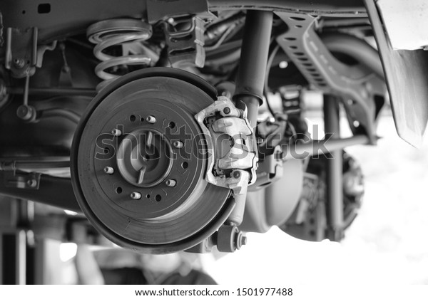 Disc brake of the vehicle for repair, in process of new
tire replacement. Car brake repairing in garage.Suspension of car
for maintenance brakes and shock absorber systems.Close up.       

