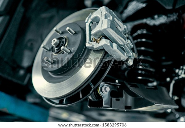 Disc brake of the vehicle for repair, in process of\
new tire replacement. Car brake repairing in garage.Suspension of\
car for maintenance brakes and shock absorber systems.Close\
up.