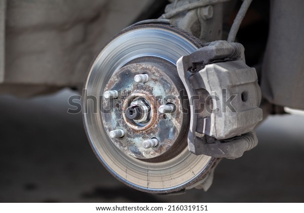 Disc brake of the vehicle for repair, in process of\
new tire replacement. Car brake repairing in garage.Suspension of\
car for maintenance brakes and shock absorber systems. Replacement\
of brake pads.