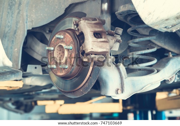 Disc brakes on cars in process of new tires\
replacement in the garage or auto repair service center, as\
background automotive concept, Adjust\
tone.