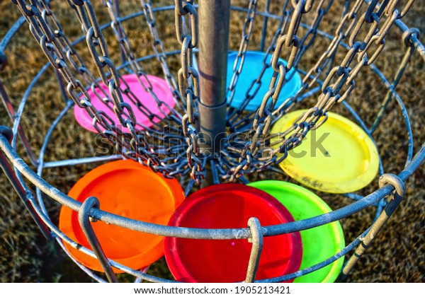 Disc golf basket with discs. The\
metal parts of the basket are selectively in\
focus.