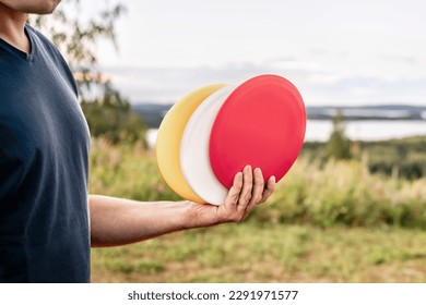 Disc golf. Discgolf or ultimate equipment. Park course and nature landscape. Throwing to target, goal or basket. Sport tournament. Hobby, training or fitness exercise. Green grass in the background.