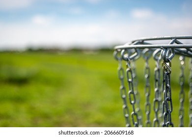 Disc golf goal chains gently swaying in the breeze with a green course in the background