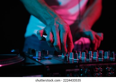 Disc jockey mixing techno music on rave party. Club dj playing set on stage. Disk jokey adjusting volume frequency regulator on sound mixer  - Shutterstock ID 2224433535