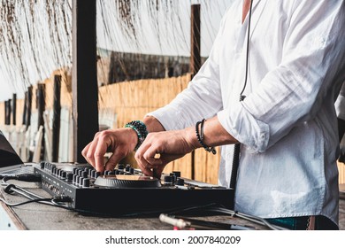 Disc jockey playing music for tourist people at club party outdoors on the beach - Dj at music live event - Live event, music and fun concept - Entertainment and party concept - Focus on hands