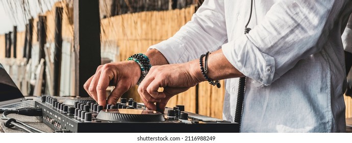 Disc jockey playing music for tourist people at the beach - Dj at music live event - Live event, music and fun concept - Entertainment and party concept - Focus on hands