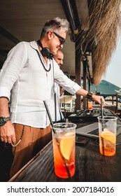 Disc jockeys playing music for tourist people at club party outdoors on the beach - Djs wearing headphones at music live event - Music and fun concept - Entertainment and party concept with drinks