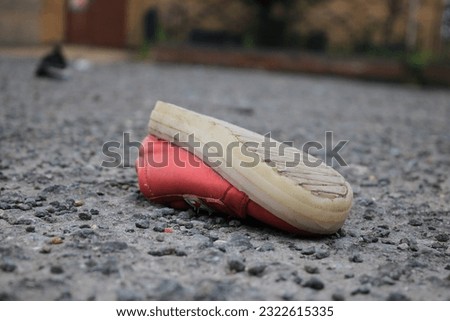 Discarded children's pink shoe upside down in a public space