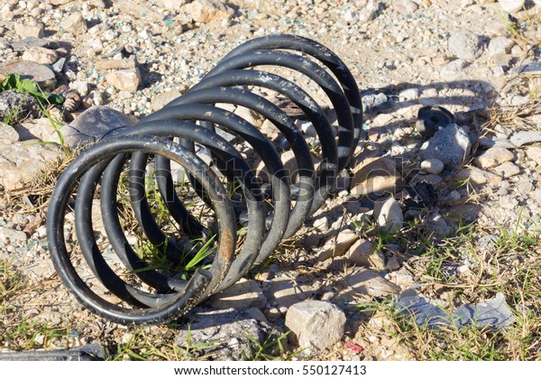 discarded coiled\
spring casting a shadow on\
rocks