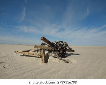 Discarded objects on sandy beach with blue sky