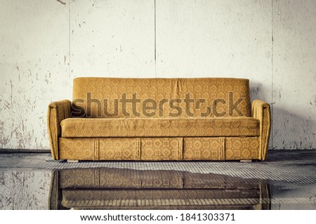 Discarded old brown sofa against dirty wall