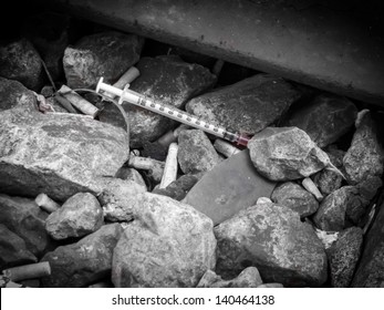 Discarded Syringe And Loose Caps From The Needles Lying Amongst Stones, Conceptual Of Drug Abuse And Addiction