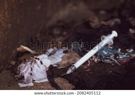 Discarded used hypodermic needle in gutter